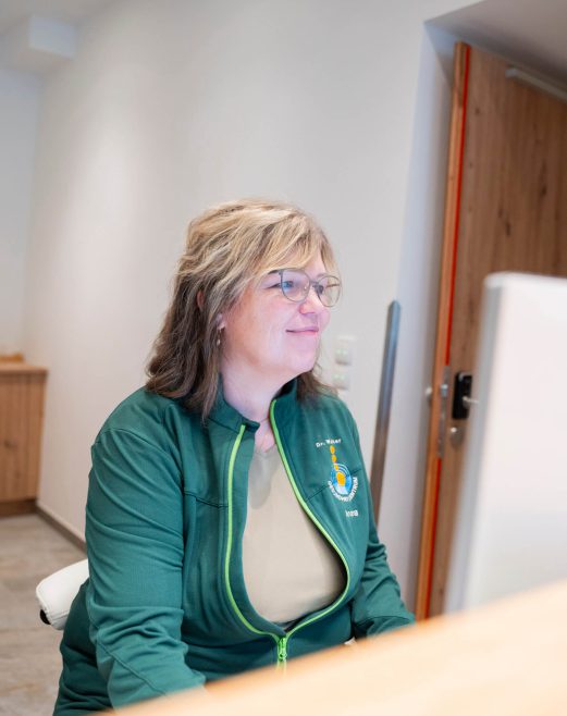 Mitarbeiterin im Gesundheitszentrum Radstadt arbeitet am Computer, freundlich und professionell.