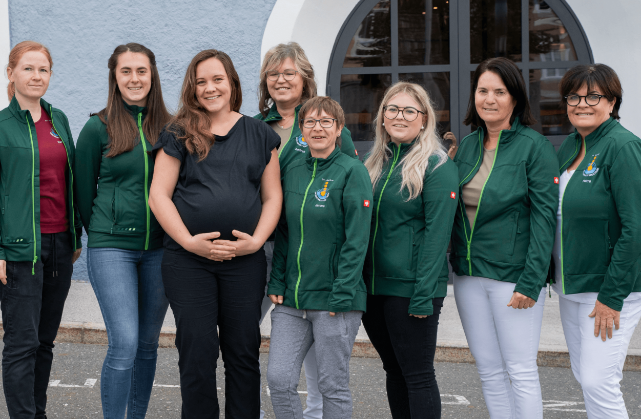 Team des Gesundheitszentrums Radstadt vor der Einrichtung, lächelnd in grünen Jacken.